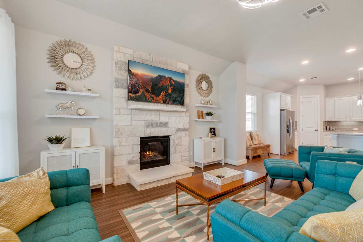 Living room moderno con divani turchesi, cuscini a contrasto, tappeto geometrico e camino in pietra bianca, atmosfera accogliente e dettagli decor pop.